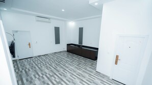 A spacious room with a checkered floor, white walls, and a built-in kitchen area. - Bona Hostel PP (Phnom Penh)