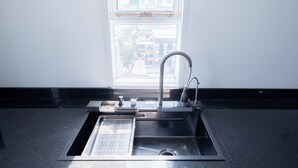 A modern kitchen with a stainless steel sink, a faucet, and a window above it. - Bona Hostel PP (Phnom Penh)