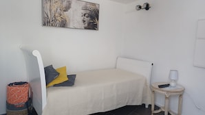 Ein Schlafzimmer mit einem Bett, Kissen, einem Nachttisch mit Lampe und einer Wandleuchte.