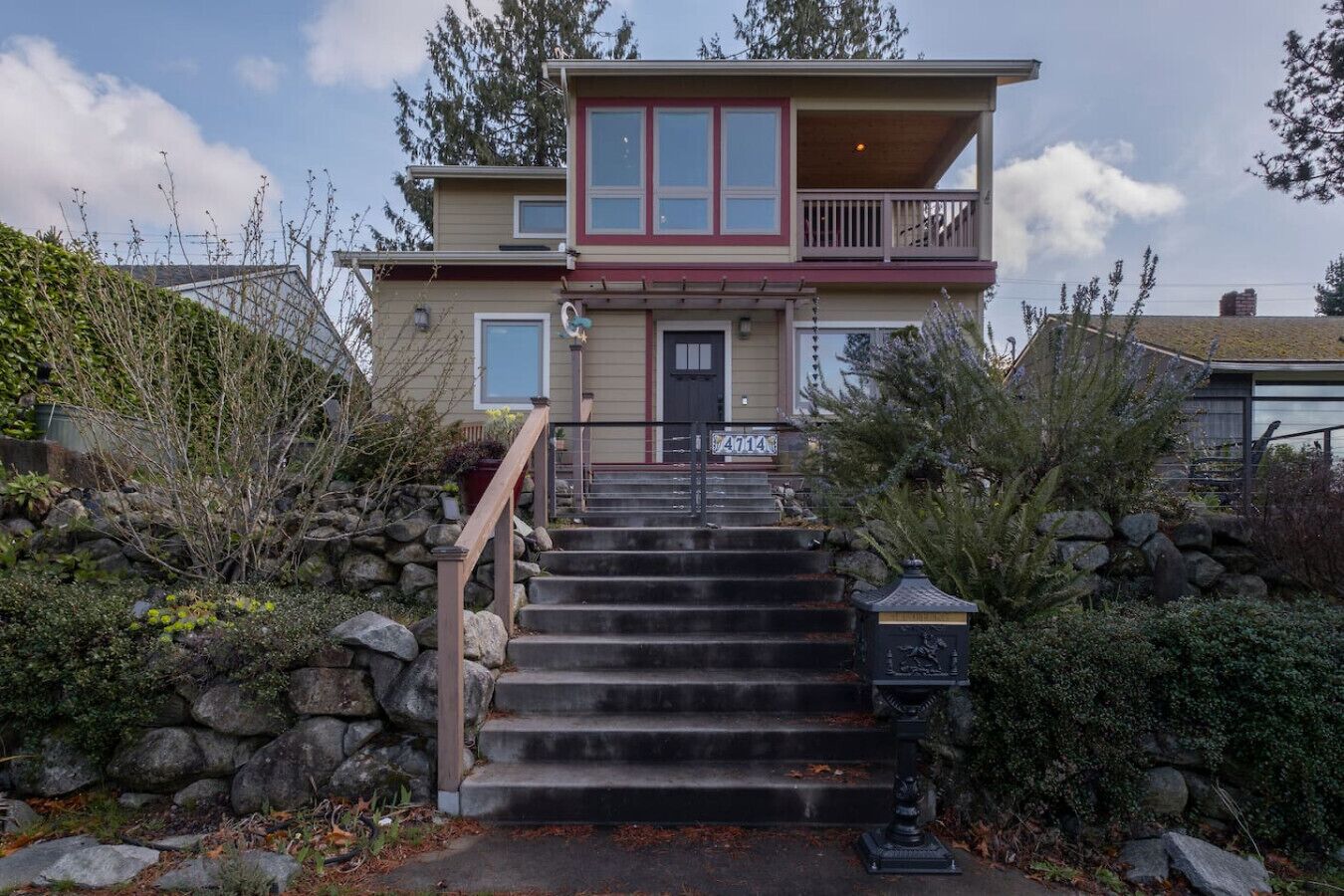 A two-story house with a front porch, a set of stone steps leading to the entrance, and a mailbox.