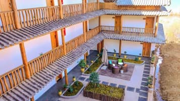 Un patio tradicional con varios niveles de balcones de madera, plantas en macetas y una zona de estar central.