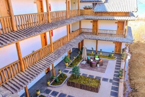 Un patio tradicional con varios niveles de balcones de madera, plantas en macetas y una zona de estar central.