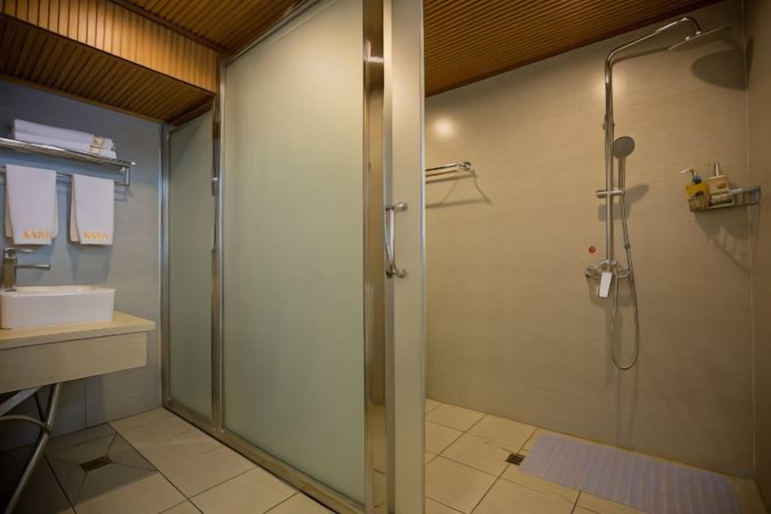 Un baño con cabina de ducha de vidrio, un lavabo y un perchero para toallas.