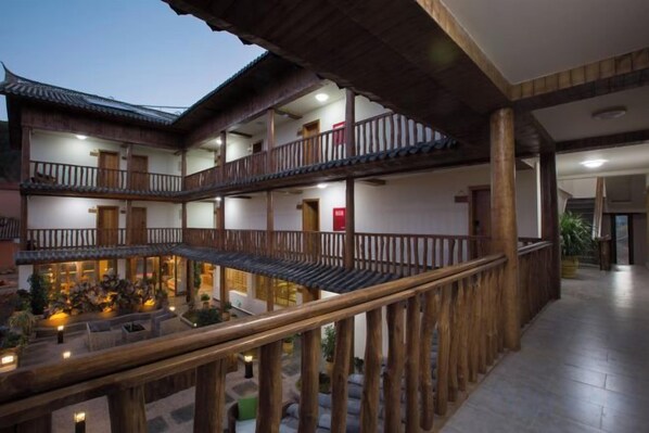 A multi-level wooden building with balconies, a courtyard, and a wooden railing.
