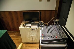 Un panel de control con monitor y teclado, una mesa de mezclas y una pantalla de proyección.