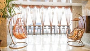 A spacious room with a large window, a hanging chair, and a seating area with tables and chairs. - Regal Hotel (Jiamusi Railway Station Department Store) (Jiamusi)