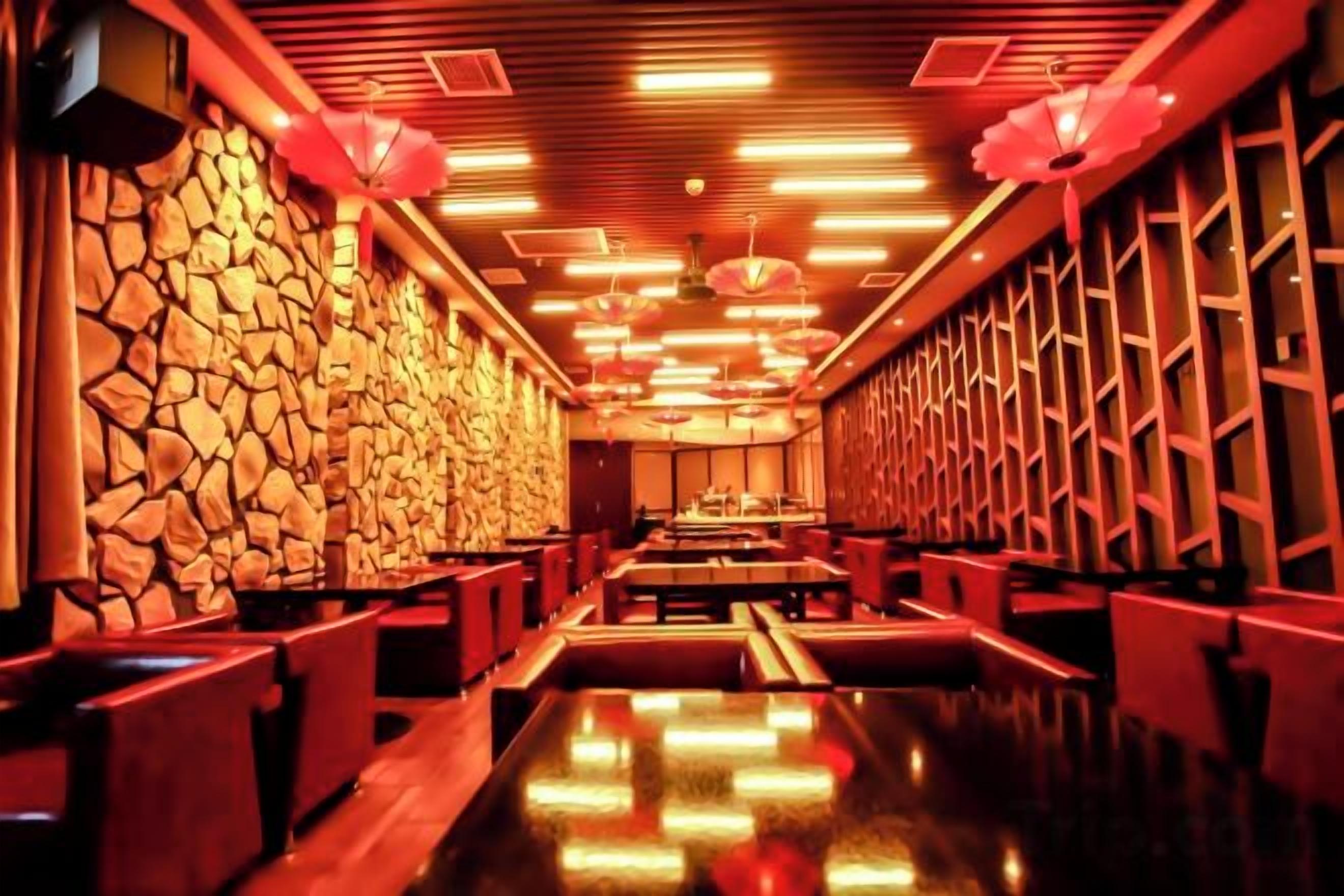 Un restaurante con pared de piedra, techo de madera e iluminación roja.