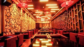 Un restaurante con pared de piedra, techo de madera e iluminación roja.