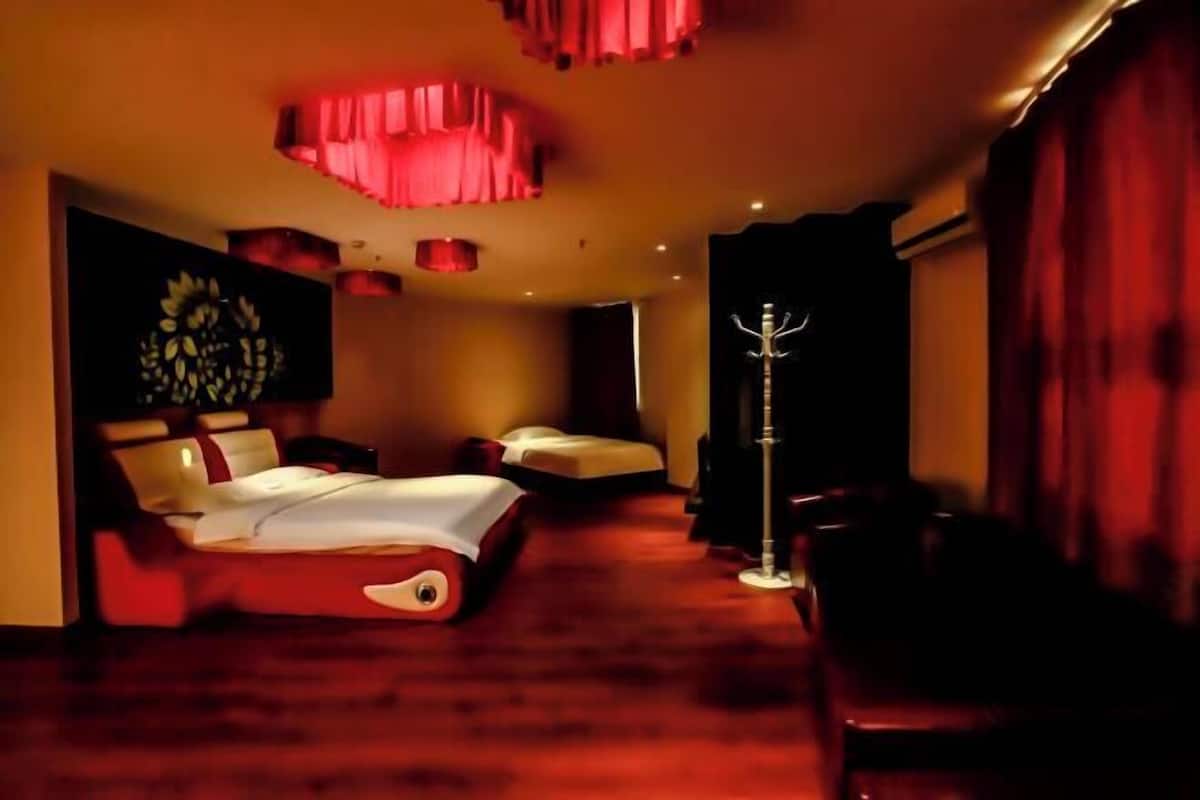 A hotel room with a large bed, a bedside table, a chair, and a floor lamp.