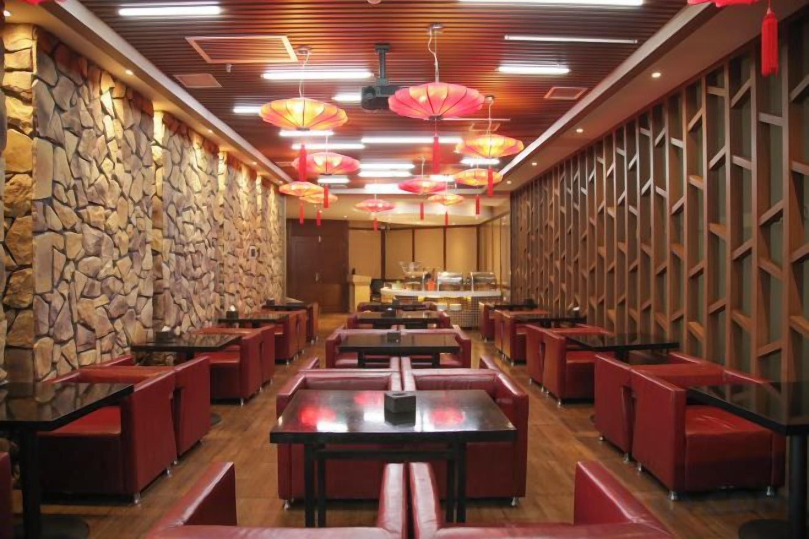 A restaurant interior with stone walls, red booths, and hanging red lanterns.
