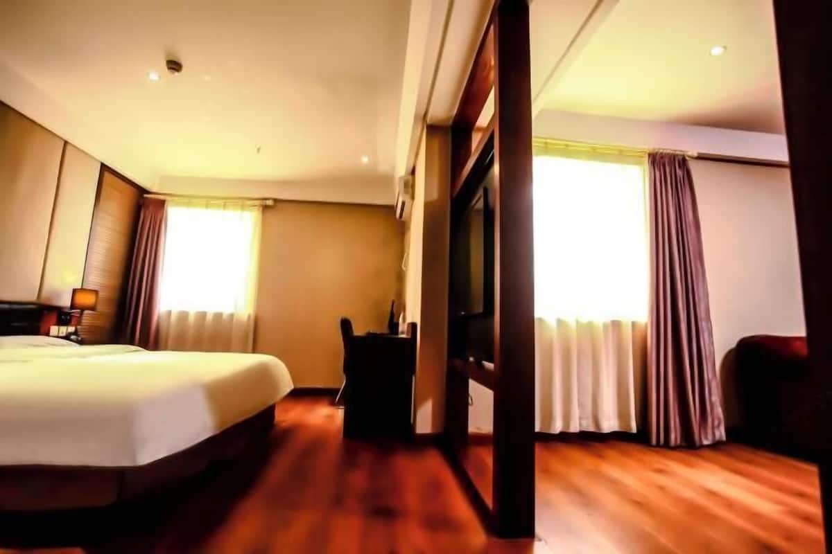 A hotel room with a bed, a desk, a chair, and a television.