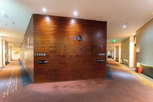 Zona de recepción con mostrador de madera, extintor y un pasillo con puertas e iluminación.