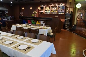 A restaurant with multiple tables set for dining, a bar area with shelves of bottles, and a counter. - Regal Hotel (Jiamusi Railway Station Department Store) (Jiamusi)
