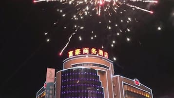 A building with a sign that reads 'Hotel Business Hotel' and a large illuminated sign above it.