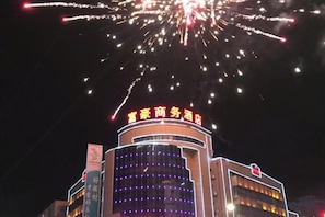 A building with a sign that reads 'Hotel Business Hotel' and a large illuminated sign above it. - Regal Hotel (Jiamusi Railway Station Department Store) (Jiamusi)