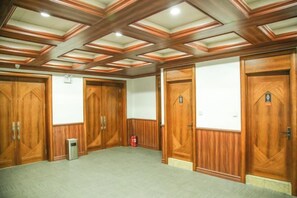 A conference room with wooden paneling, a carpeted floor, and a ceiling with recessed lighting. - Regal Hotel (Jiamusi Railway Station Department Store) (Jiamusi)