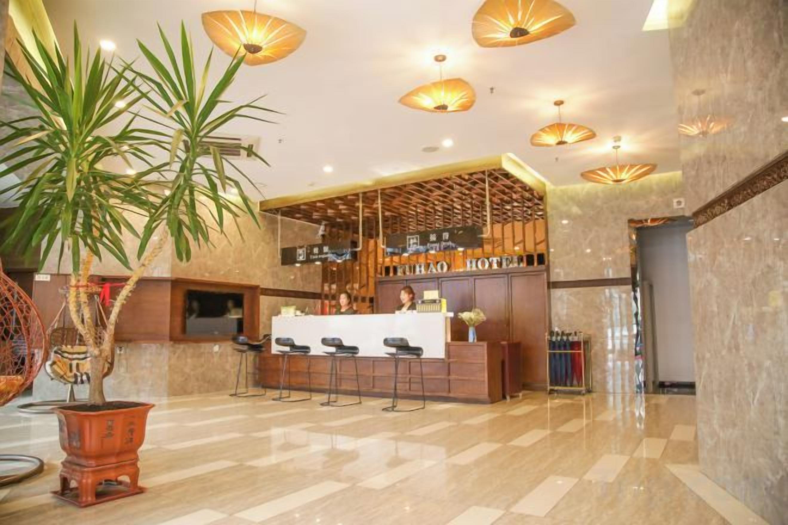 A hotel lobby with a reception desk, seating area, and a large potted plant.
