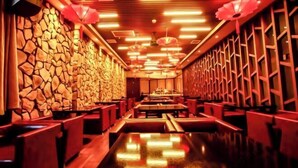 A restaurant with a stone wall, red seating, and a long counter. - Regal Hotel (Jiamusi Railway Station Department Store) (Jiamusi)