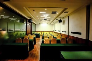 A conference room with rows of tables and chairs, a projector screen, and a stage area. - Regal Hotel (Jiamusi Railway Station Department Store) (Jiamusi)