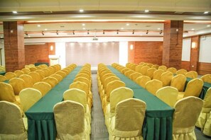 A conference room with rows of tables and chairs, a projector screen, and a brick wall. - Regal Hotel (Jiamusi Railway Station Department Store) (Jiamusi)