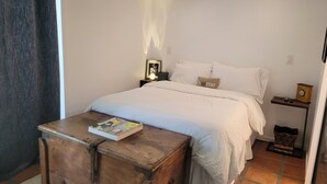Un dormitorio con cama, mesita de noche y un cofre de madera.