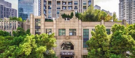 A multi-story building with a central entrance, surrounded by trees.