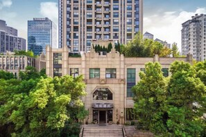 A multi-story building with a central entrance, surrounded by trees. - Youzhi Hotel (Hangzhou)