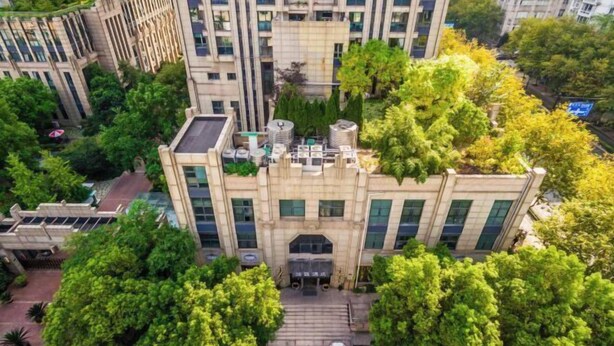 A multi-story building with a central entrance, surrounded by lush greenery and adjacent smaller structures. - Youzhi Hotel (Hangzhou)