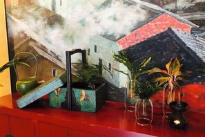 Una superficie roja con una pintura de un edificio y una pequeña composición floral.