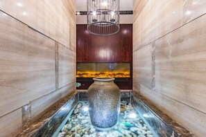 A spa area with a large stone basin, a fish tank, and a modern light fixture.