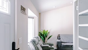 A modern living room with a grey sectional sofa, a grey armchair, and a potted plant. - Modern Minimalist Home 4BR 5 Beds, AC Comfort & Wifi (Burlington)
