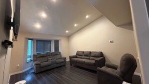A living room with two sofas, a coffee table, and a robotic vacuum cleaner. - Modern Minimalist Home 4BR 5 Beds, AC Comfort & Wifi (Burlington)
