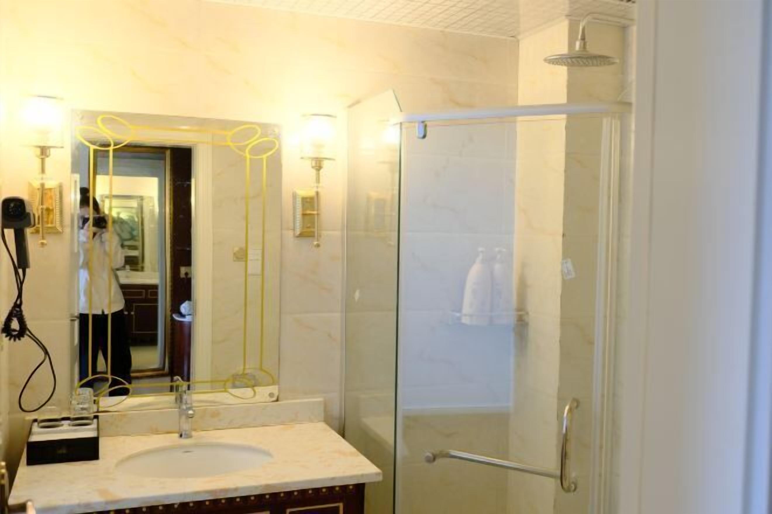 Un baño con cabina de ducha de vidrio, un lavabo con espejo e iluminación en la pared.