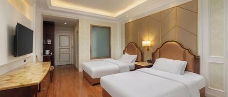 A hotel room with two beds, a TV, a desk, and a bathroom visible through an open door.