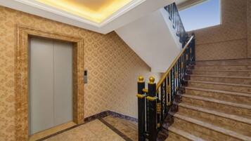 A hotel interior with a carpeted staircase, a door, and a patterned wall.