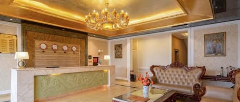 A spacious lobby with a reception desk, a chandelier, and a plush sofa.