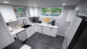 Una cocina moderna con armarios blancos, encimera negra y un ventanal amplio.