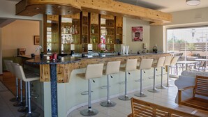Een bar met een houten toog, meerdere krukken en uitzicht op het buitenterras.