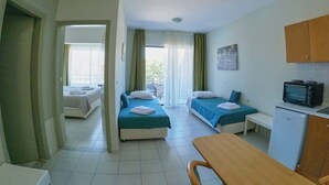 Een hotelkamer met twee bedden, een tafeltje, een televisie en een koelkast.