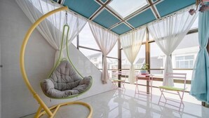 Een moderne kamer met een hangstoel, een tafeltje en uitzicht op buiten.