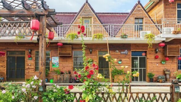 Een houten gebouw met een traditioneel ontwerp, met meerdere balkons en een houten pergola met hangende lantaarns.