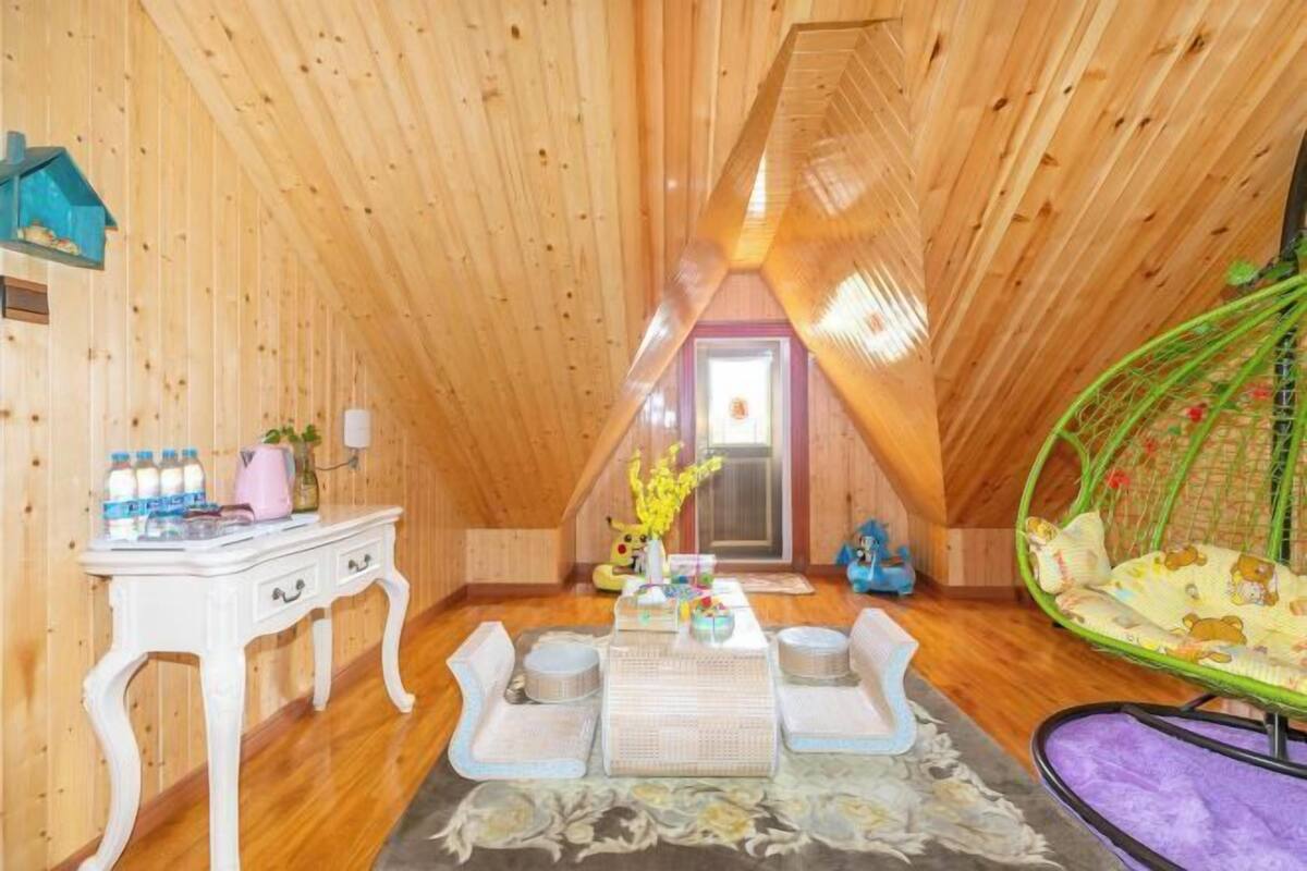 Een gezellige zolderkamer met houten wanden, een witte kapstok, een groene hangstoel en een kleine tafel met een vaas.