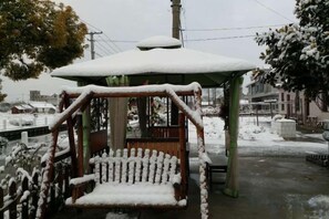 A gazebo with a bench, covered in snow, in a snowy outdoor setting. - Tianyingju Farmhouse (Shanghai)