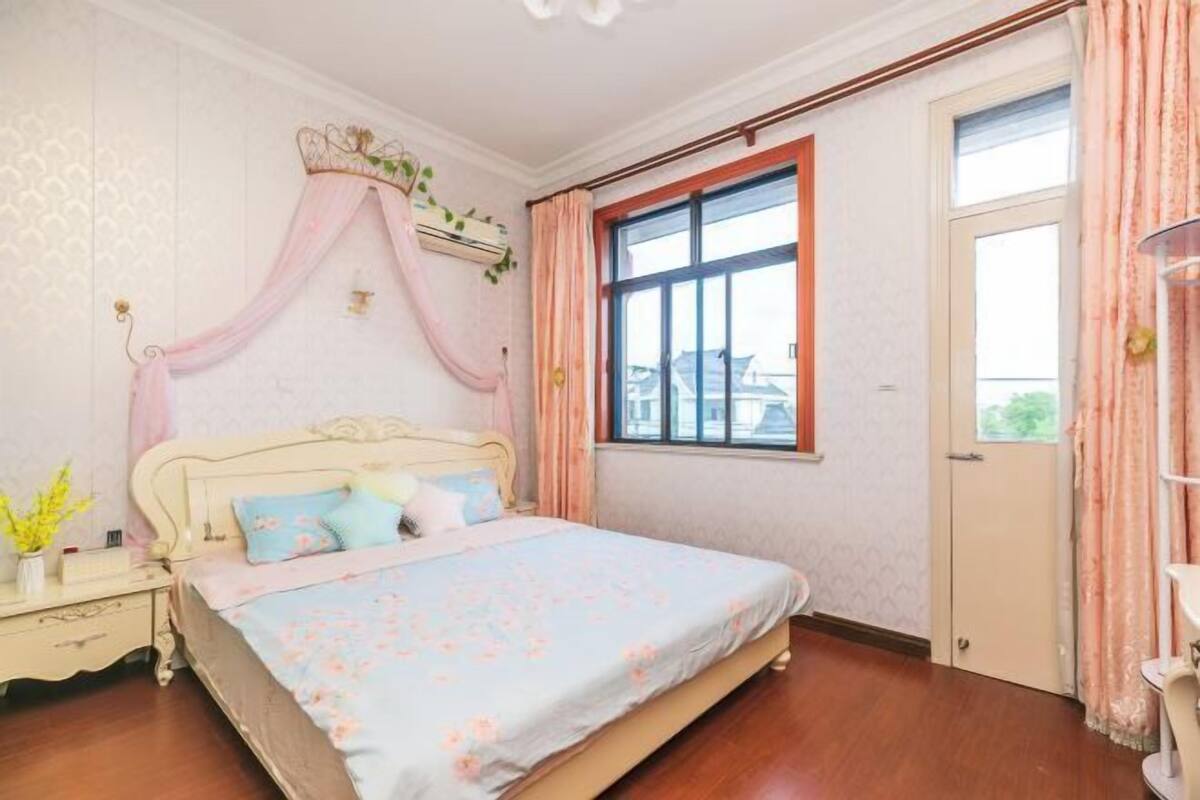 Een slaapkamer met een bed, nachtkastje, raam en deur.