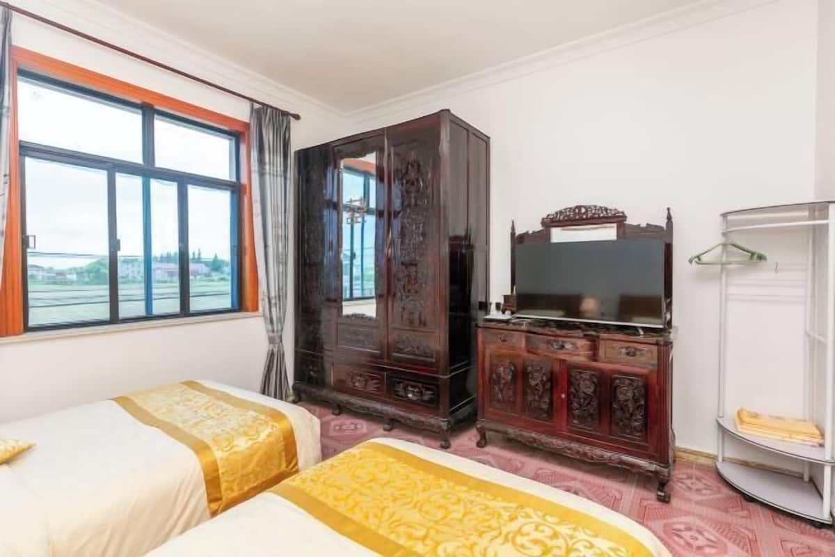 Een hotelkamer met twee bedden, een grote houten kast, een televisie en een garderobekast.