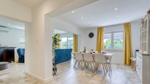 Cocina moderna con comedor, que presenta una mesa grande con sillas, un sofá azul y una planta.