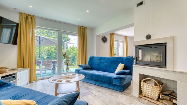 Una sala moderna con un sofá azul, una mesa de centro blanca y una chimenea.