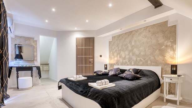 A modern bedroom with a large bed, bedside tables, a mirror, and a wardrobe. - Cosy Home D&D by Interhome (Brod Moravice)