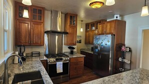 A kitchen with wooden cabinets, stainless steel appliances, granite countertops, and pendant lighting. - Lake Coeur d'Alene Inn Guest House (Coeur d'Alene)