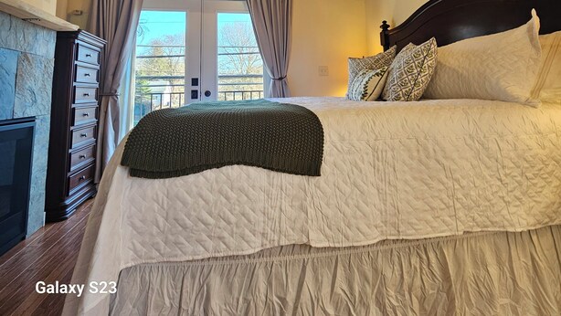 A bedroom with a bed, a ceiling fan, a fireplace, and a view of the outdoors. - Lake Coeur d'Alene Inn Guest House (Coeur d'Alene)